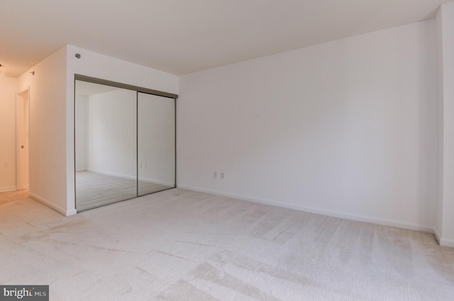 unfurnished bedroom with a closet and light colored carpet