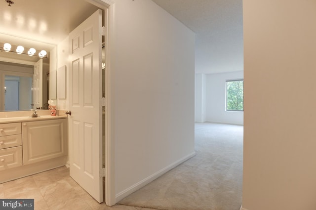 hall featuring sink and light carpet