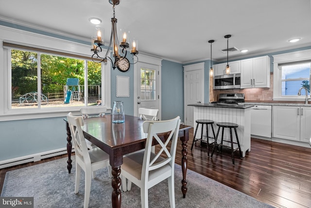 dining area featuring sink, dark wood-type flooring, crown molding, and an inviting chandelier