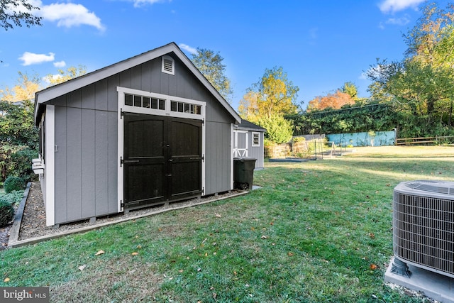 view of outbuilding with central AC unit and a lawn