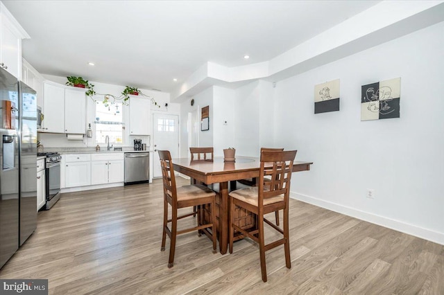 dining area with sink and light wood-type flooring