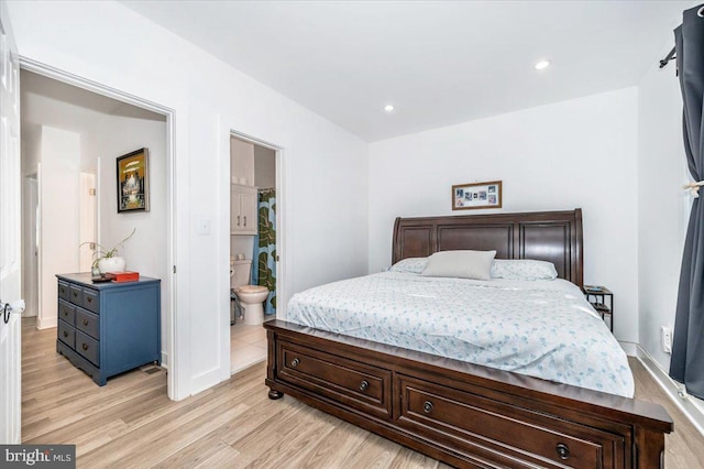 bedroom featuring connected bathroom and light hardwood / wood-style flooring