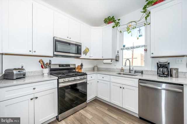 kitchen featuring sink, appliances with stainless steel finishes, light hardwood / wood-style flooring, and white cabinetry