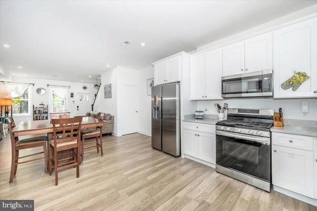 kitchen with light hardwood / wood-style flooring, white cabinets, and stainless steel appliances