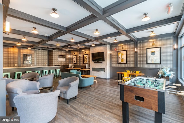 recreation room with beam ceiling, wood finished floors, coffered ceiling, and a premium fireplace