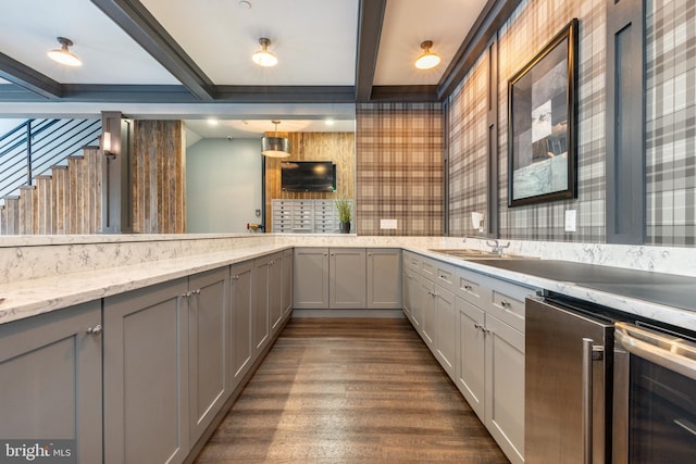 kitchen with light stone countertops, dark wood-style flooring, beam ceiling, gray cabinets, and beverage cooler