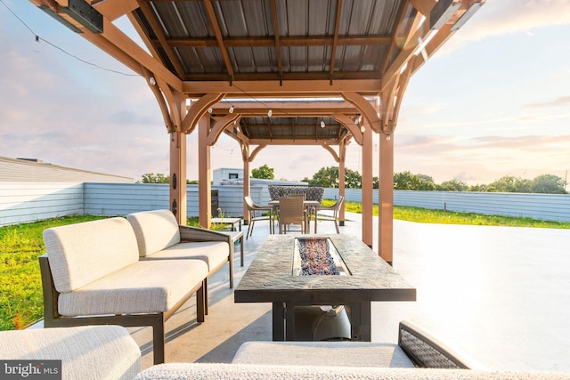 patio terrace at dusk with a gazebo, outdoor dining space, and an outdoor living space with a fire pit