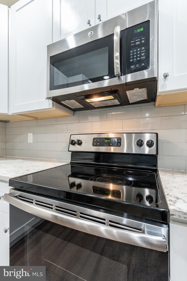 kitchen featuring appliances with stainless steel finishes, white cabinetry, and light stone counters