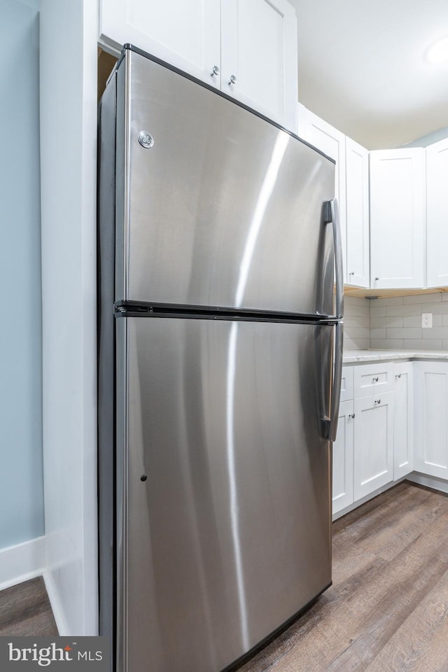 kitchen featuring stainless steel fridge, white cabinets, hardwood / wood-style floors, and backsplash