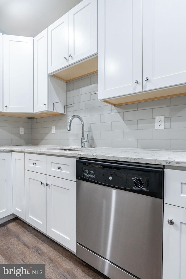 kitchen featuring decorative backsplash, white cabinets, dark hardwood / wood-style flooring, stainless steel dishwasher, and light stone counters