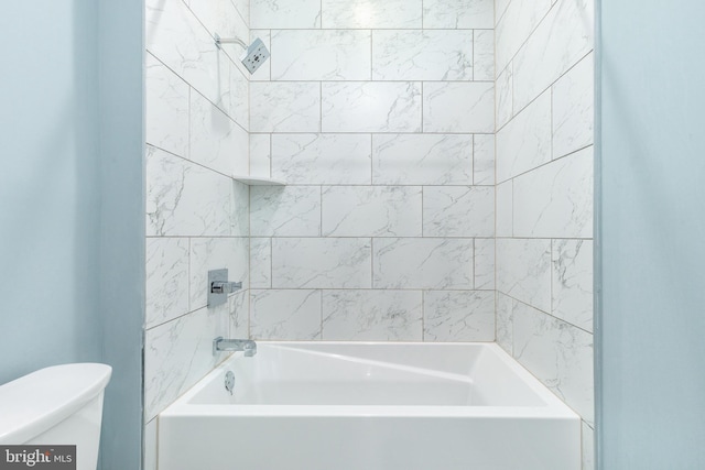 bathroom featuring toilet and tiled shower / bath