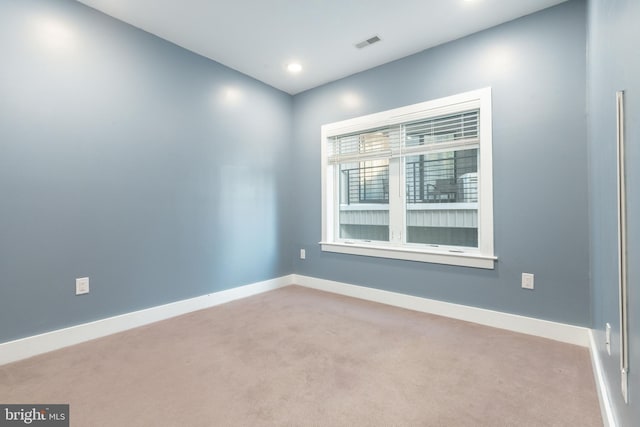empty room featuring visible vents, light carpet, and baseboards