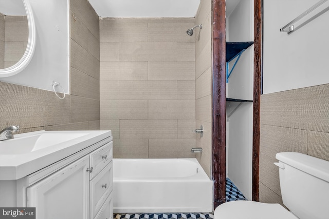 full bathroom featuring vanity, toilet, tile walls, and tiled shower / bath