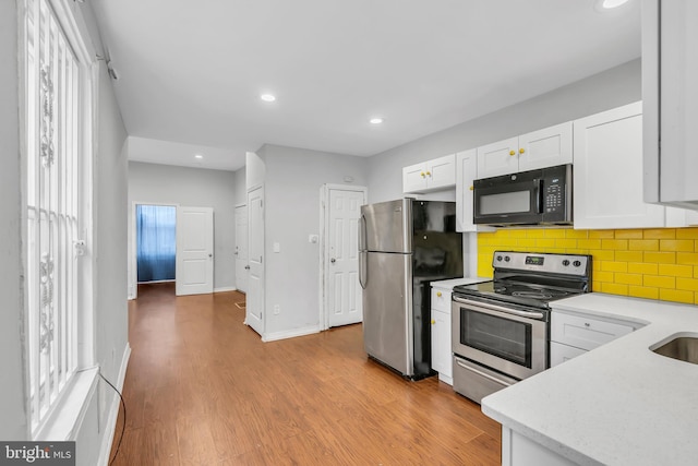 kitchen with white cabinets, light hardwood / wood-style floors, stainless steel appliances, and tasteful backsplash