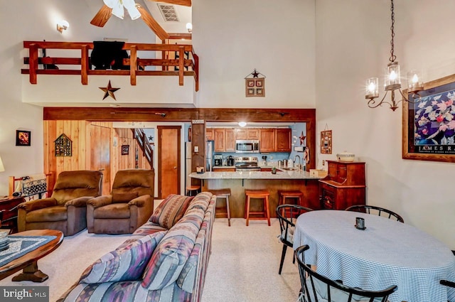 living room with sink, a high ceiling, light carpet, and ceiling fan with notable chandelier