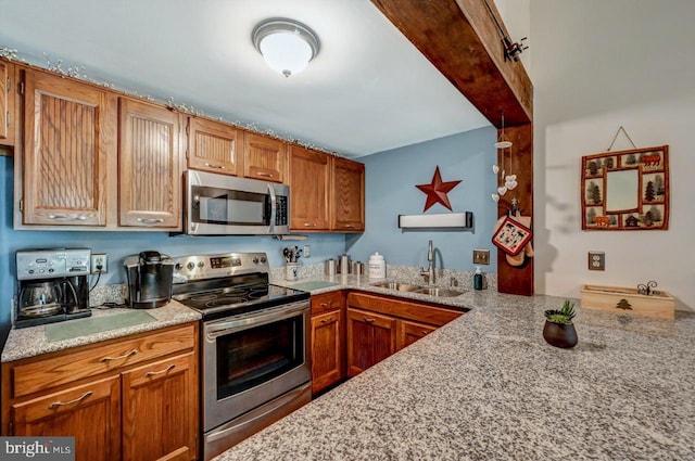 kitchen with appliances with stainless steel finishes, light stone countertops, and sink