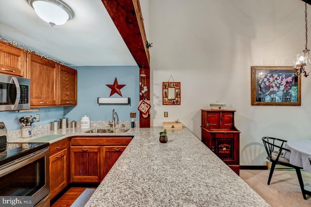 kitchen with light carpet, hanging light fixtures, light stone countertops, sink, and stainless steel appliances