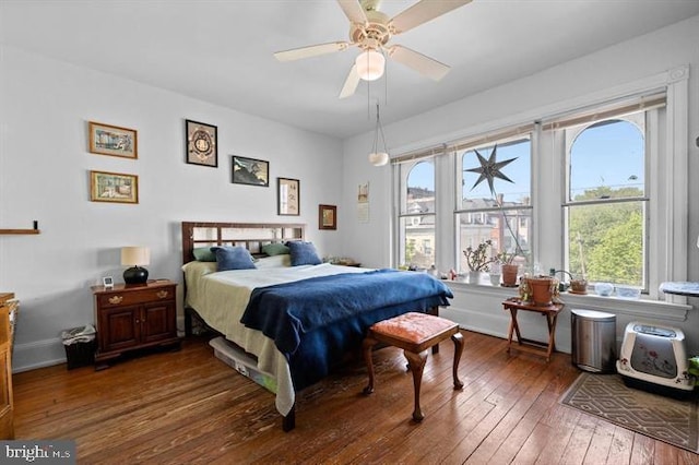 bedroom featuring multiple windows, dark hardwood / wood-style floors, and ceiling fan