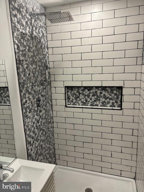 bathroom featuring tiled shower and vanity