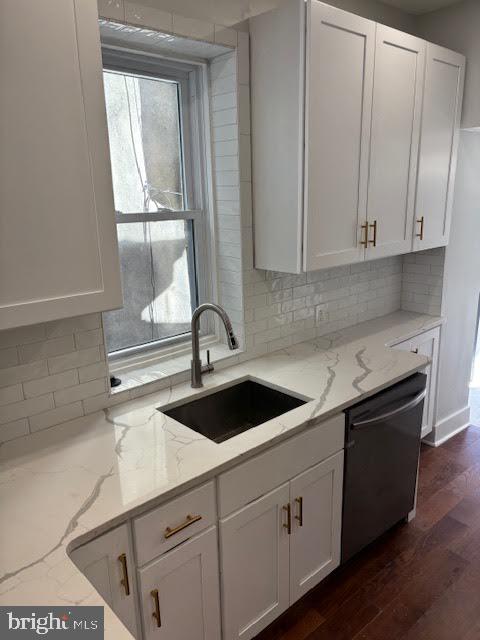 kitchen with decorative backsplash, black dishwasher, and light stone countertops