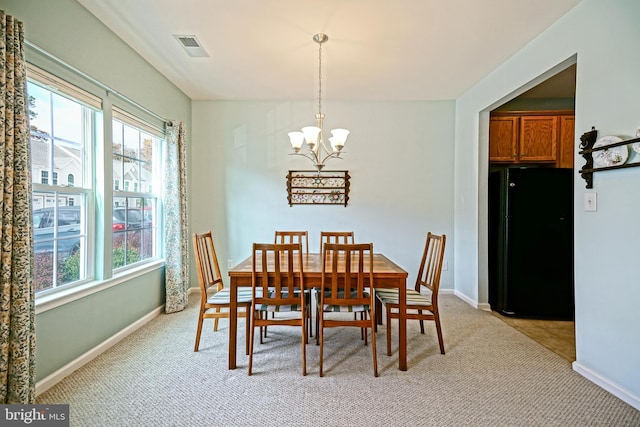 carpeted dining area with an inviting chandelier