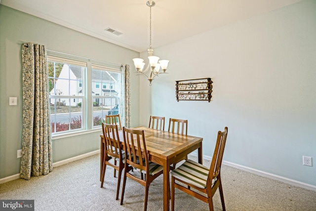 carpeted dining area with a chandelier