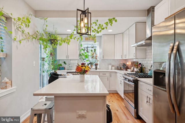 kitchen featuring tasteful backsplash, wall chimney range hood, light countertops, a kitchen breakfast bar, and stainless steel appliances