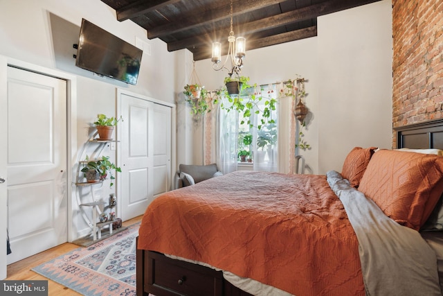 bedroom featuring beamed ceiling, wood ceiling, and light wood finished floors