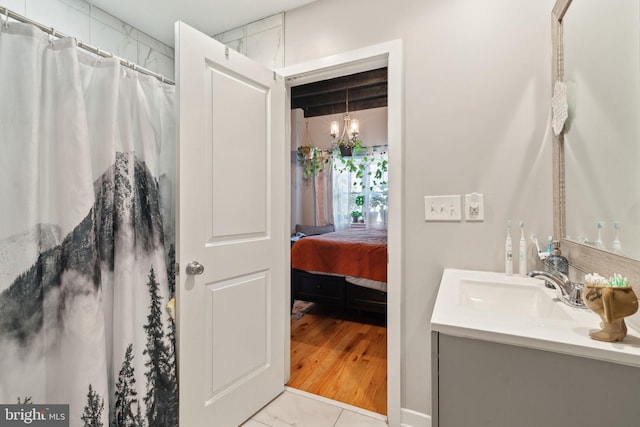 ensuite bathroom featuring a shower with shower curtain, connected bathroom, an inviting chandelier, and vanity