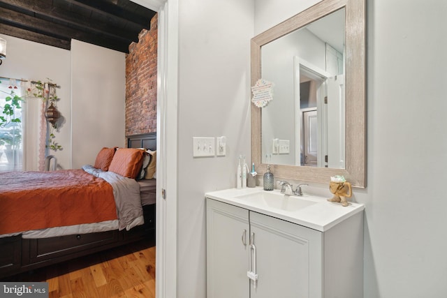 bathroom featuring beam ceiling, connected bathroom, vanity, and wood finished floors