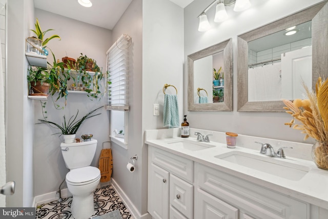 bathroom featuring double vanity, toilet, baseboards, and a sink