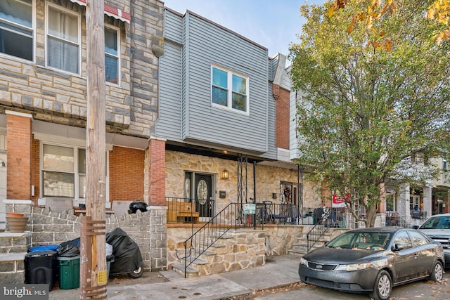 multi unit property featuring stone siding, brick siding, and covered porch