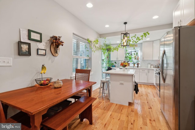 kitchen with light wood finished floors, a kitchen island, stainless steel appliances, white cabinets, and light countertops