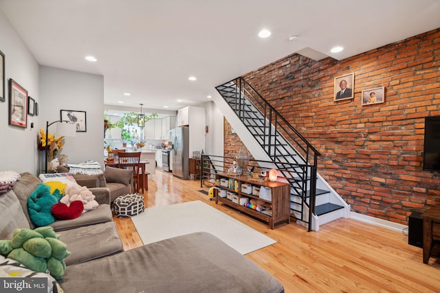 living room with stairway, recessed lighting, brick wall, and light wood-type flooring