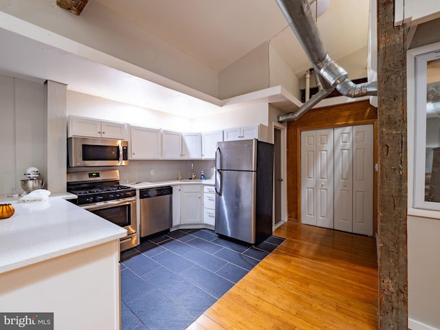 kitchen featuring dark hardwood / wood-style flooring, appliances with stainless steel finishes, white cabinetry, high vaulted ceiling, and sink