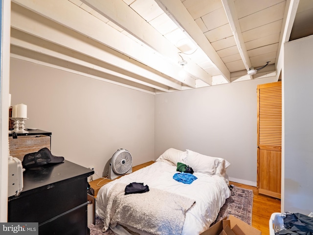 bedroom with beamed ceiling and hardwood / wood-style floors