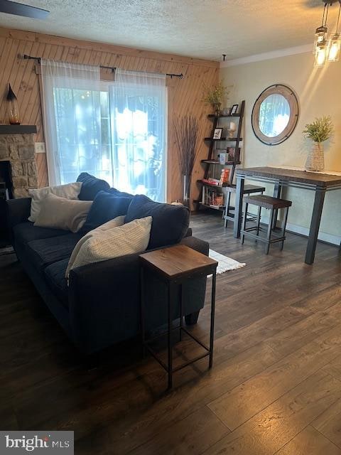 living room featuring a fireplace, a textured ceiling, wooden walls, and dark hardwood / wood-style floors