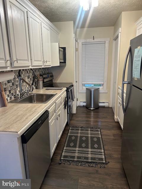 kitchen with a textured ceiling, white cabinets, stainless steel appliances, and dark hardwood / wood-style flooring