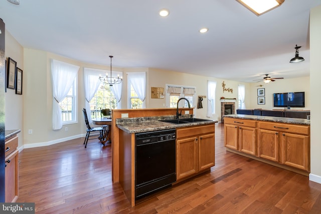 kitchen featuring black dishwasher, sink, dark hardwood / wood-style flooring, decorative light fixtures, and a kitchen island with sink