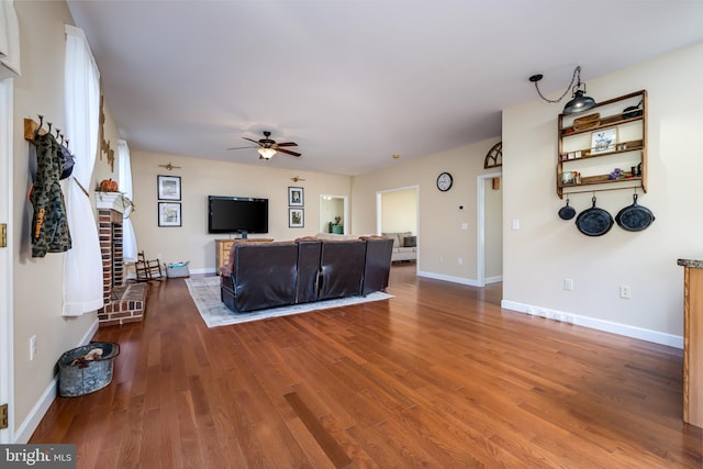 living room with a fireplace, wood-type flooring, and ceiling fan