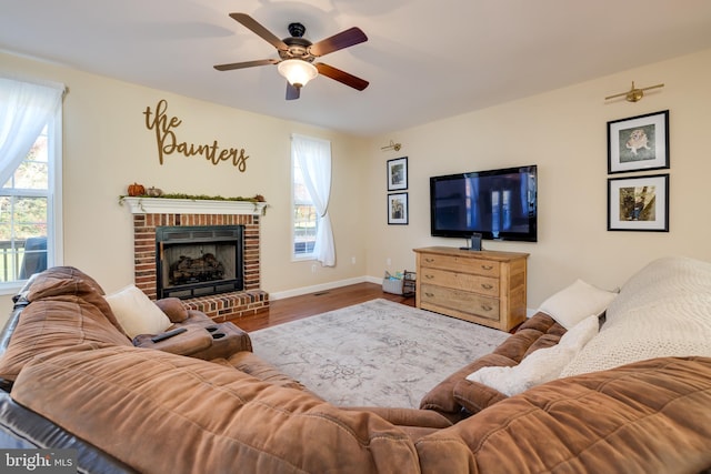 living room featuring a fireplace, wood-type flooring, and ceiling fan