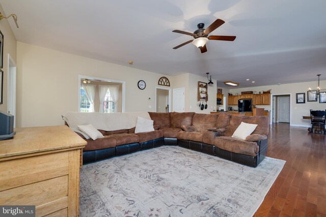 living room featuring dark hardwood / wood-style flooring and ceiling fan with notable chandelier