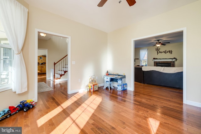 interior space with ceiling fan, wood-type flooring, a fireplace, and a wealth of natural light