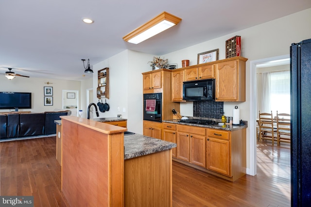 kitchen featuring kitchen peninsula, backsplash, ceiling fan, black appliances, and dark wood-type flooring