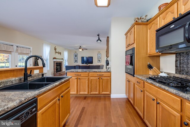 kitchen featuring ceiling fan, light hardwood / wood-style flooring, black appliances, a fireplace, and sink