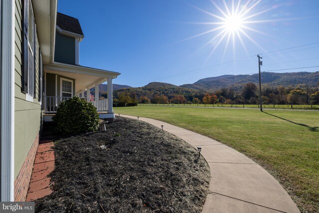 view of yard with a mountain view, covered porch, and a rural view