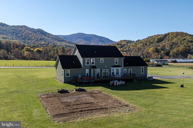 rear view of house with a lawn and a deck with mountain view