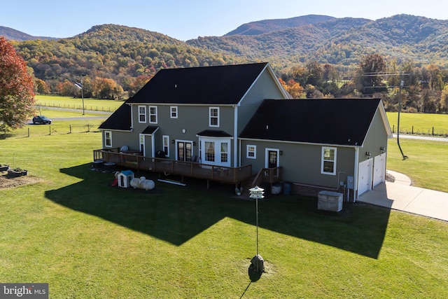 rear view of house featuring a deck with mountain view and a lawn