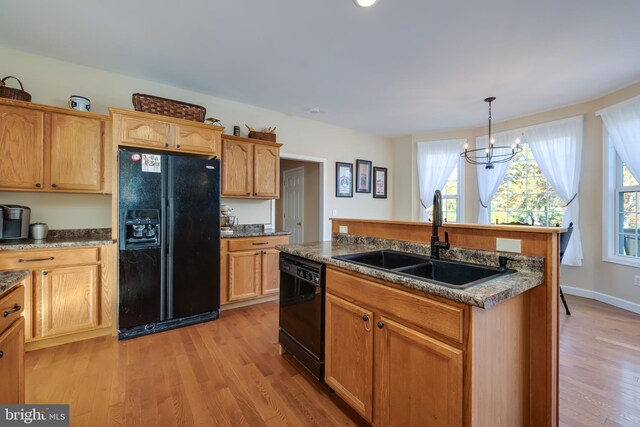 kitchen featuring an inviting chandelier, black appliances, pendant lighting, light hardwood / wood-style floors, and sink