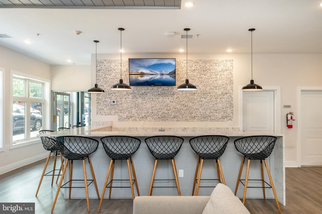 kitchen with light stone countertops, dark wood-type flooring, and pendant lighting